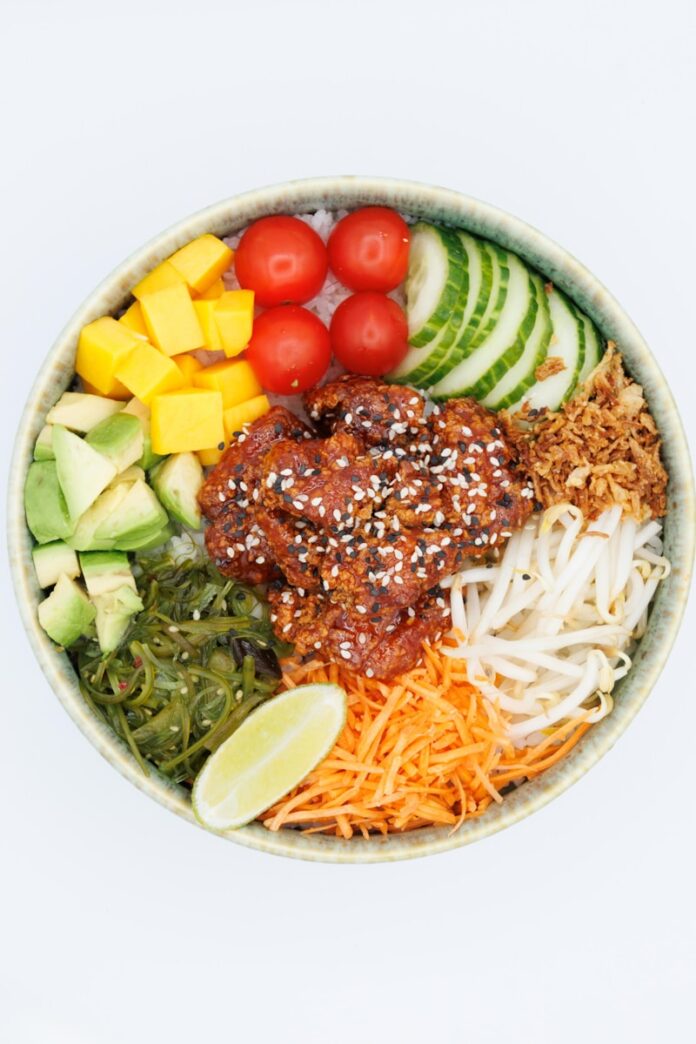 A colorful poke bowl with fresh ingredients and chicken.
