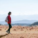 일상 속 ‘마음챙김 걷기’, 건강과 힐링을 한 번에 a man with a backpack walking across a dry grass covered field