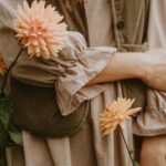 집에서도 실천 가능한 ‘마음 챙김’ 루틴, 스트레스 시대의 건강 관리법 A person in a brown gingham dress and corduroy vest among peach dahlias